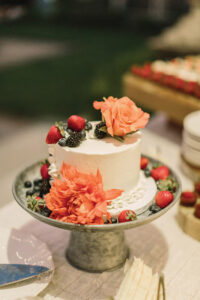 A cake decorated with fruit and flowers from Off the Beaten Path Weddings